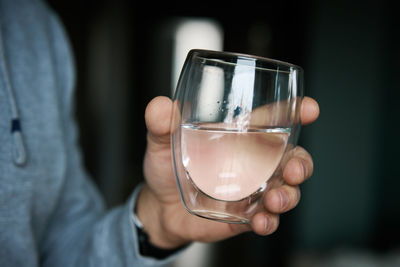 Man drinks water, close-up shot of man holding glass of fresh water, quenching thirst