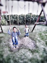 Children playing on swing in park