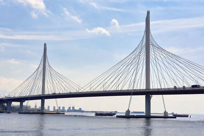 Suspension bridge over river against cloudy sky