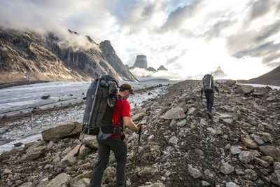 Two backpackers hike over glacial moraine to reach mountains ahead.