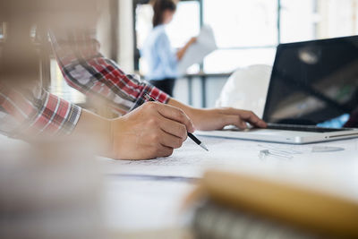 Close-up of architects drawing blueprint on paper in office