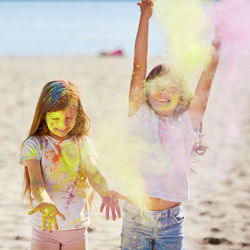 Happy children throw bright paints and smiling on the beach