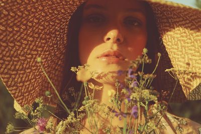 Close-up portrait of young woman with flowers in sunlight