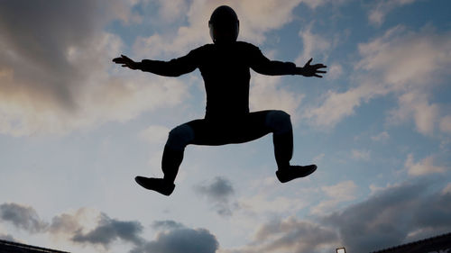 Low angle view of silhouette man jumping against sky