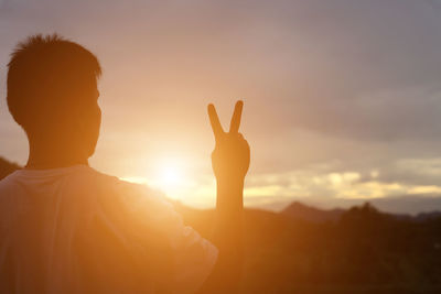 Rear view of silhouette man against sky during sunset