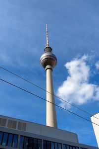 Low angle view of communications tower against cloudy sky