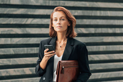 Portrait of young woman standing against wall