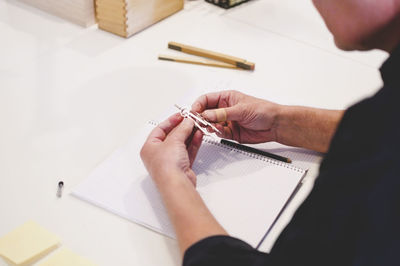 Cropped image of senior businessman adjusting drawing compass at desk in creative office