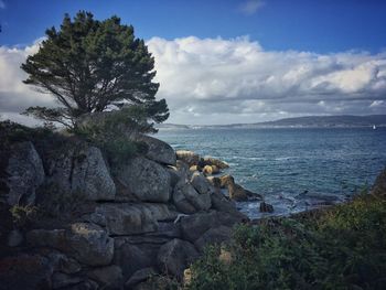 Scenic view of rocks by sea against sky