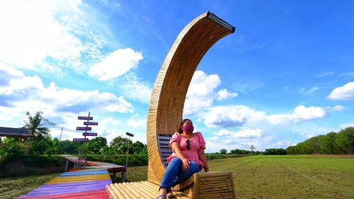 Full length of woman sitting on field against sky