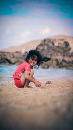 Side view portrait of smiling girl playing with sand at beach