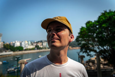 Portrait of young man looking away against sky
