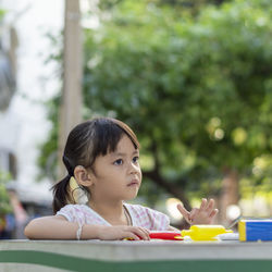 Close-up of cute girl playing with childs play clay at table outdoors