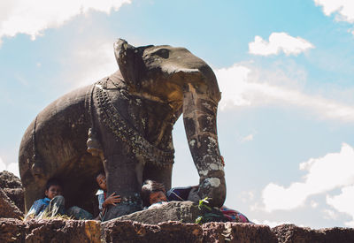 Low angle view of sculpture on rock against sky