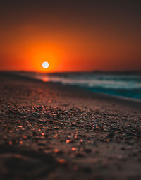 Surface level of sea against sunset sky