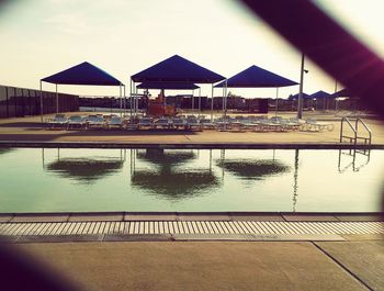 Lounge chairs by swimming pool by building against sky