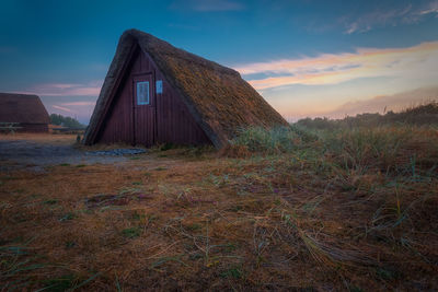 Abandoned house on field against sky during sunset