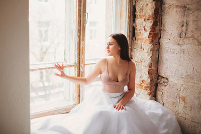 Full length of woman sitting on window