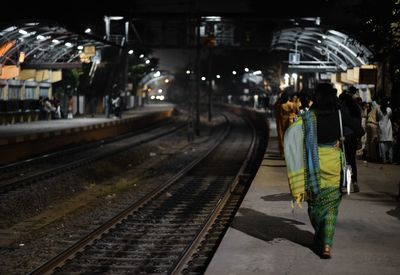 Rear view of people walking on railroad station