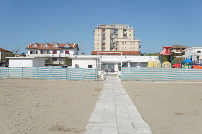 Buildings by swimming pool against clear blue sky