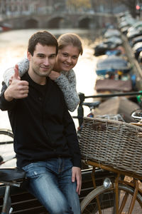 Young couple with bicycle by railing in city