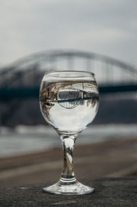 Close-up of drink at beach against bridge