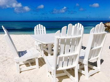 Chairs and tables on beach against sky