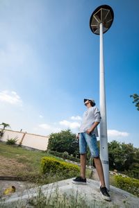 Low angle view of young man standing against sky