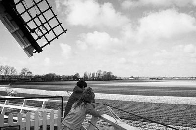 Rear view of man on railing against sky