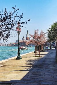 Street by footpath against sky