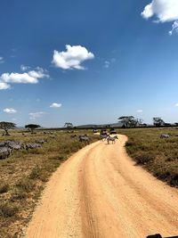 Dirt road on field against sky