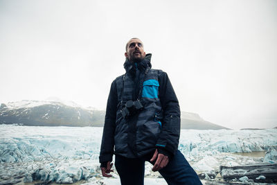 Man standing on snowcapped mountain against sky