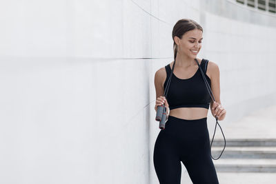 Portrait of young woman standing against wall