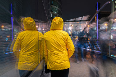 Rear view of people walking on illuminated street at night