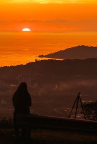 Silhouette person standing on land against sky during sunset