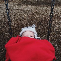 Portrait of baby in red blanket on swing