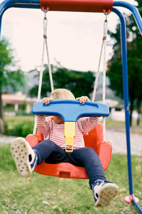 Rear view of children on swing at playground