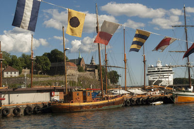 Boats moored at harbor against sky