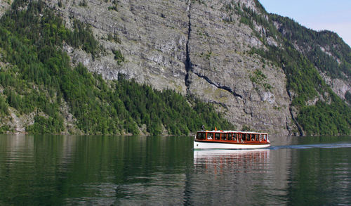 Boat sailing on sea by mountain