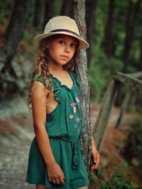 Portrait of girl standing by tree trunk in forest