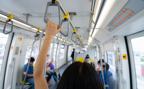 Woman hand firm grip safety handrail in elevated monorail train. mass transit system in modern city.
