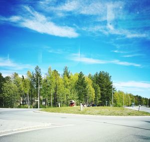 Road by trees against blue sky