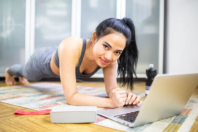 Portrait of young woman using phone while sitting on table