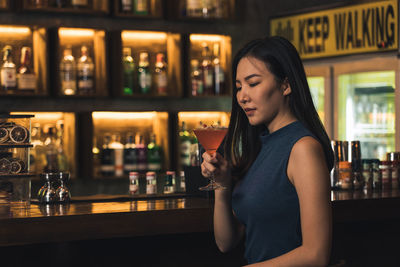 Young woman drinking glass on table at bar