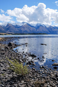 Scenic view of lake by snowcapped mountains against sky