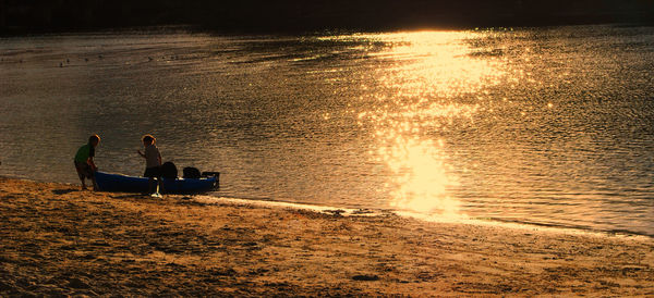 Silhouette people on boat at lake during sunset