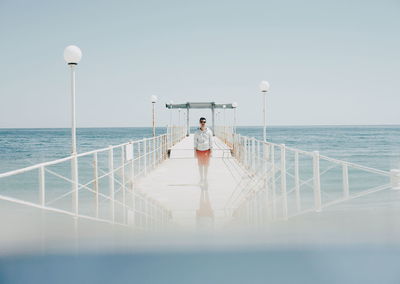 Surface level view of man standing on pier in sea