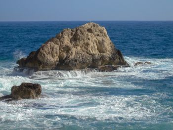 Rock formation in sea against clear sky