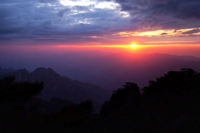 Scenic view of silhouette mountains against orange sky