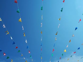 Low angle view of buntings hanging against blue sky